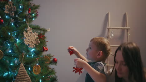 Mom-and-her-son-hang-Christmas-tree-toys-on-top-of-Christmas-tree.-High-quality-4k-footage